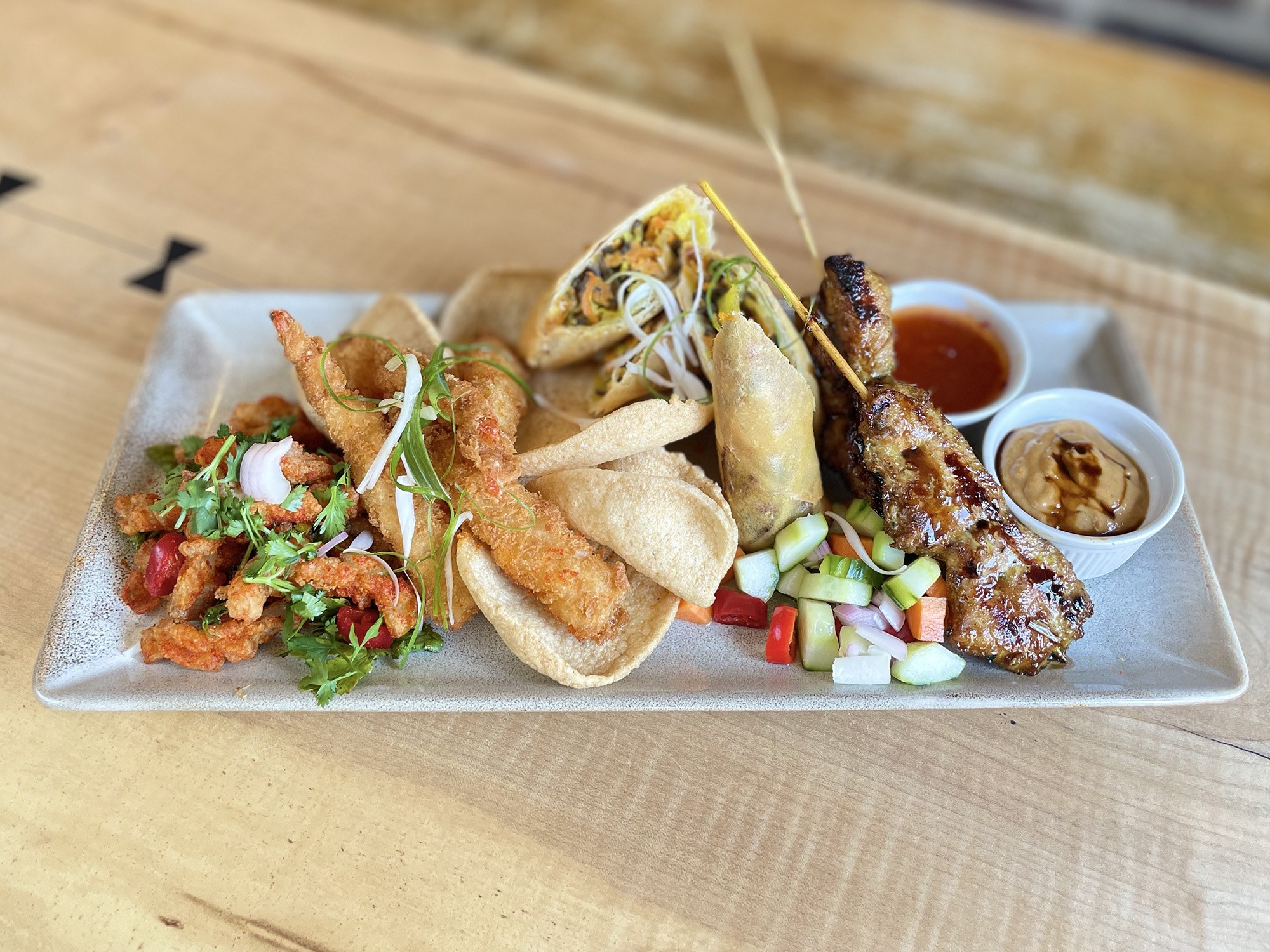 Sharing platter with satay skewers, spring rolls, squid and dipping sauces